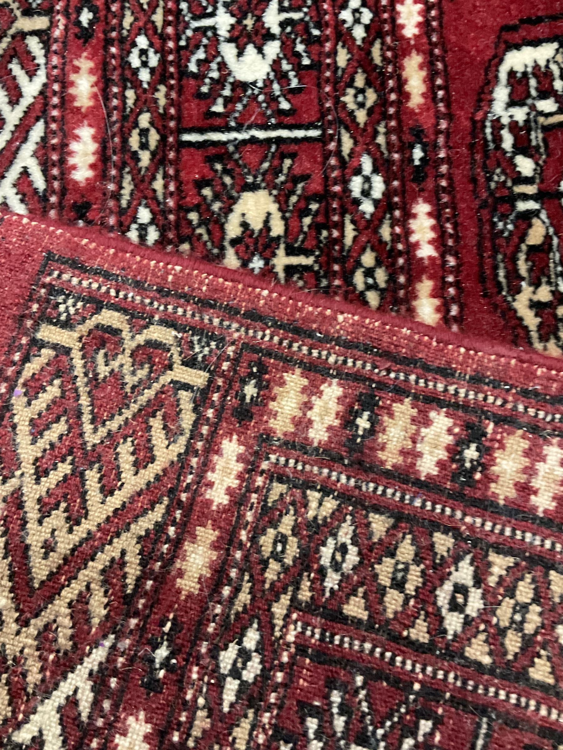 Persian Bokhara rug, red ground and decorated with single row of Gul motifs, multiple band border with geometric design