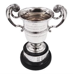 1920s silver trophy cup, with twin scroll handles and girdle, upon circular stepped foot,  the body with presentation engraving 'The Helen Andrews Memorial Cup, Handicraft Section', hallmarked Walker & Hall 1927, fixed upon ebonised wooden base with applied winners plaques, including base H18cm