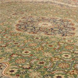 Central Persian Kashan rug, emerald green ground, with a central ivory, indigo, and brick red lobbed medallion with pendant finials, ivory spandrels, framed by multiple floral borders