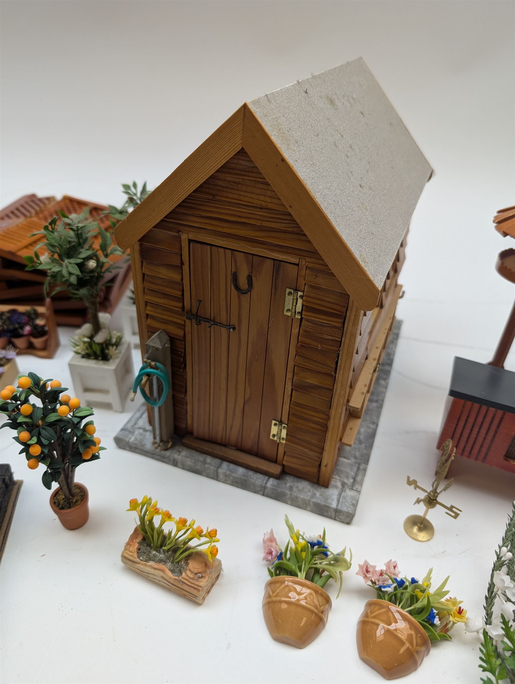 1:12 scale dolls house allotment and garden accessories, including wooden shed on a stone effect base, two vegetable patches, terracotta plant pots with flowers and foliage, stone effect plant pots, other planters, loose sunflowers, scarecrow, rabbit hutch, garden tools, fencing panels, etc 