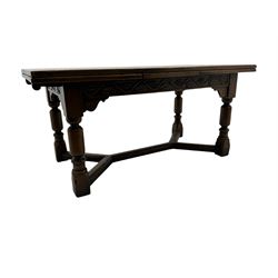 Early 20th century Jacobean design draw-leaf oak dining table, rectangular top with carved frieze depicting scrolling foliage and grape clusters, sliding extending leaves, raised on robust turned supports united by H-stretcher  