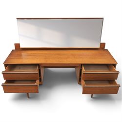 Austinsuite - mid 20th century teak headboard with bedside cabinets and matching  mirrored dressing table, the headboard with floating single drawer bedsides raised on a single tapering support, the dressing table with attached tilting mirror, above rectangular top with kneehole and two banks of two drawers, raised on tapering supports

Headboard H 84cm, D 40cm, W 229cm, W between bedsides 151cm 
Dressing table H 113cm D 44cm, W 149cm, H to underside of dresser 61cm