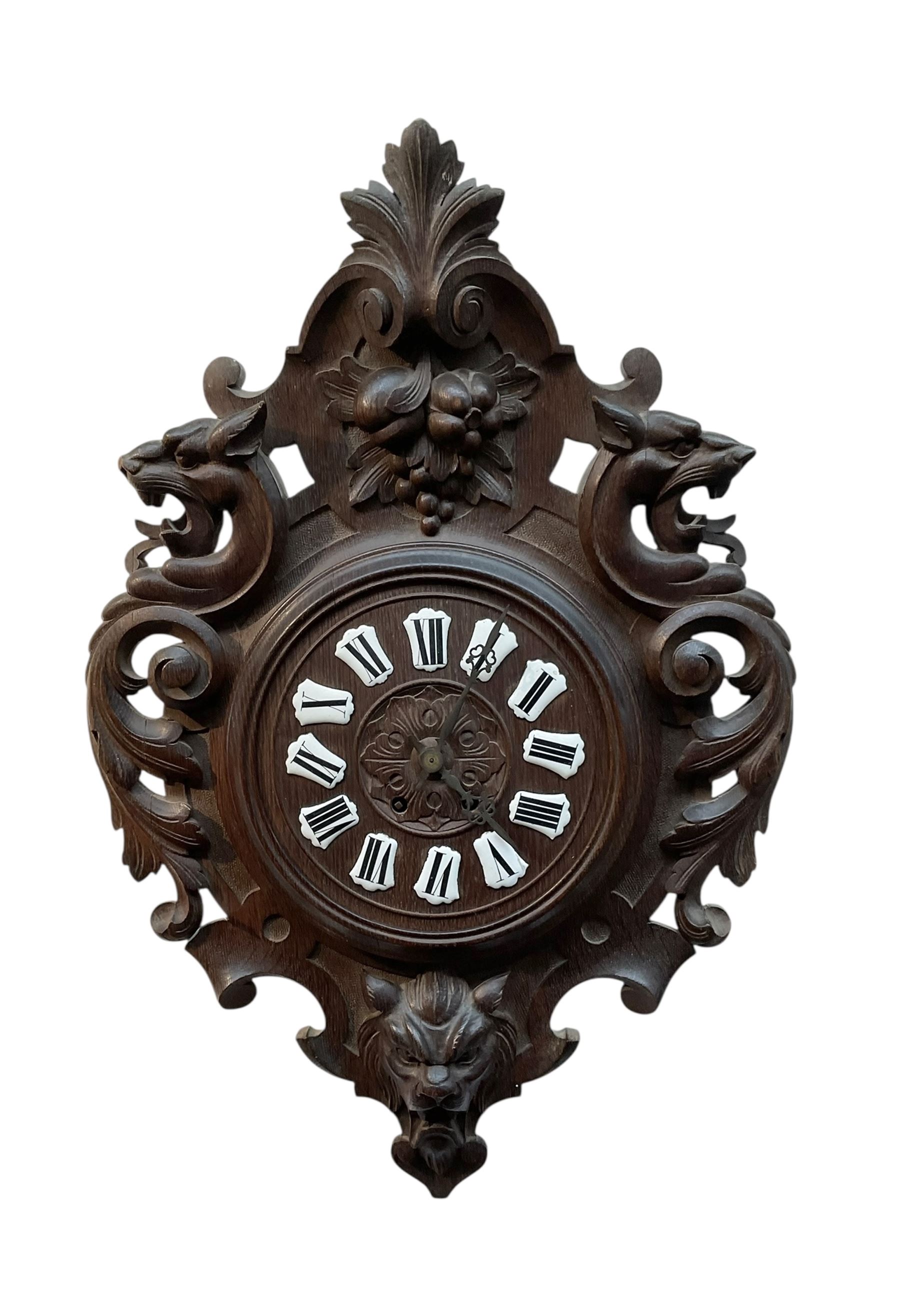 French- late 19th century carved oak wall clock c 1880, outer case with interlaced scroll carving and a carved images of fruit and wild beasts, integrated dial with porcelain cartouche Roman numerals and gothic hands, with a twin train spring driven rack striking movement striking the hours on a coiled gong.
