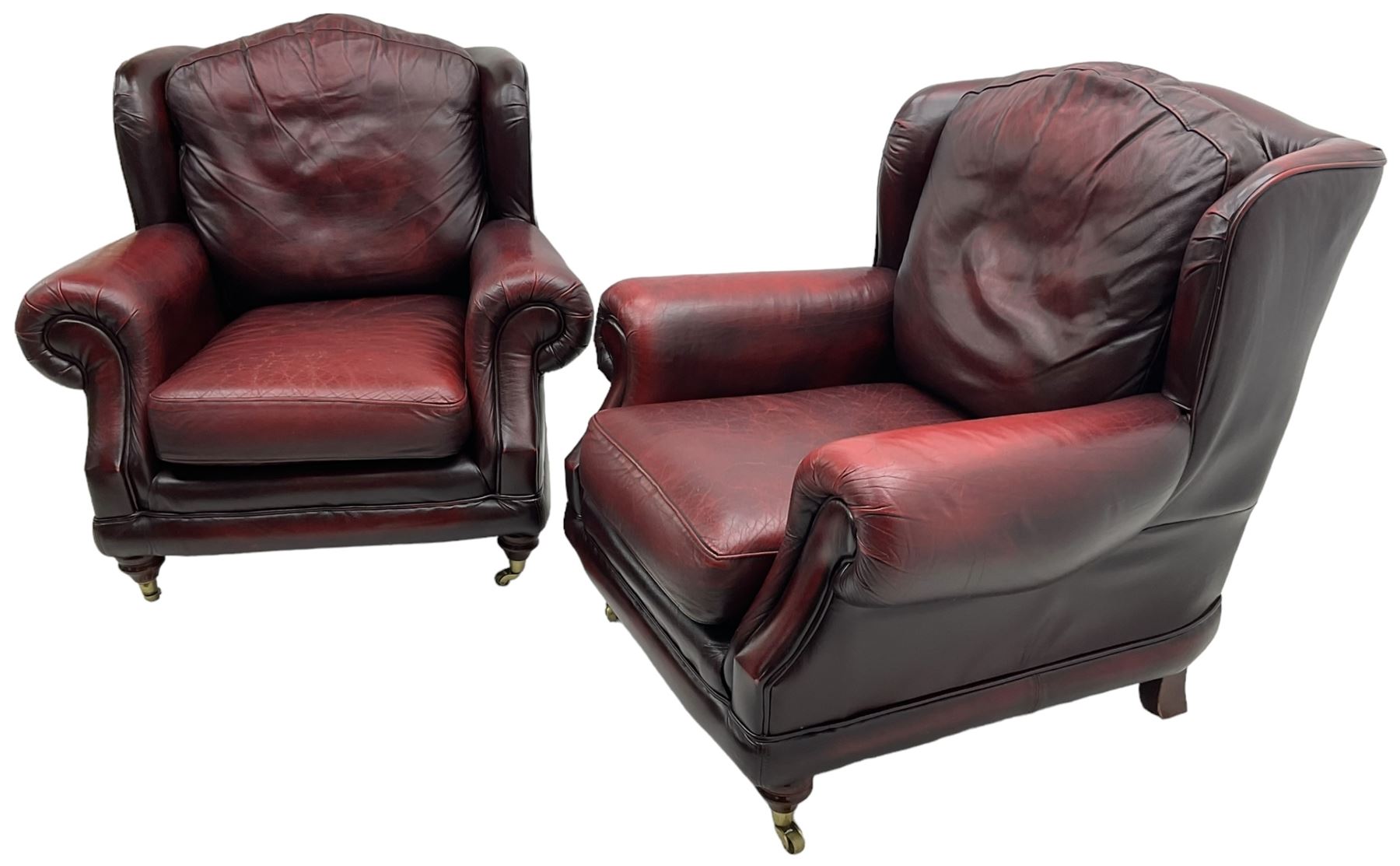 Thomas Lloyd - three-piece lounge suite, comprising of traditional shape two seat sofa (W190cm H80cm) and a pair of wingback armchairs (W100cm H91cm), each with rolled arms over turned supports with brass castors, upholstered in oxblood red leather