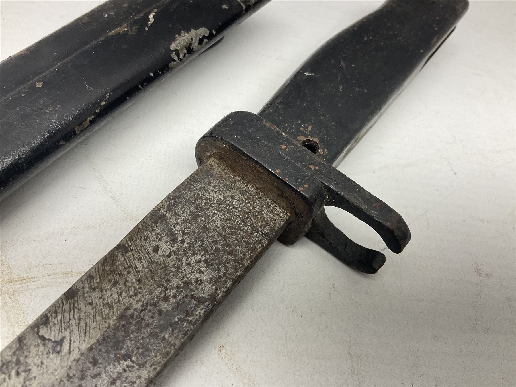 British No 7 MKI knife bayonet with 20cm single edged fullered clipped point blade;  blackened steel, large muzzle ring cross-guard; blackened swivelling pommel marked 'F5H'; red Tufnol composite grips; in blackened steel scabbard L33cm overall; British Pattern 1888 bayonet with scabbard; and German Ersatz bayonet with scabbard (3)