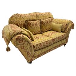 Steed Upholstery Ltd. - 'Lincoln' two-seat sofa upholstered in gold 'Olympia' floral pattern corded and tasselled fabric, together with scatter cushions and arm covers, on turned feet with brass castors