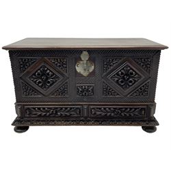 Early 20th century carved hardwood kist or mule chest of small proportions, moulded rectangular hinged lid over foliage carved geometric lozenge panels, the frame carved with chevron banding, fitted with two drawers, the drawer fronts carved with extending leaf motifs over a foliage carved lower moulding, on turned feet