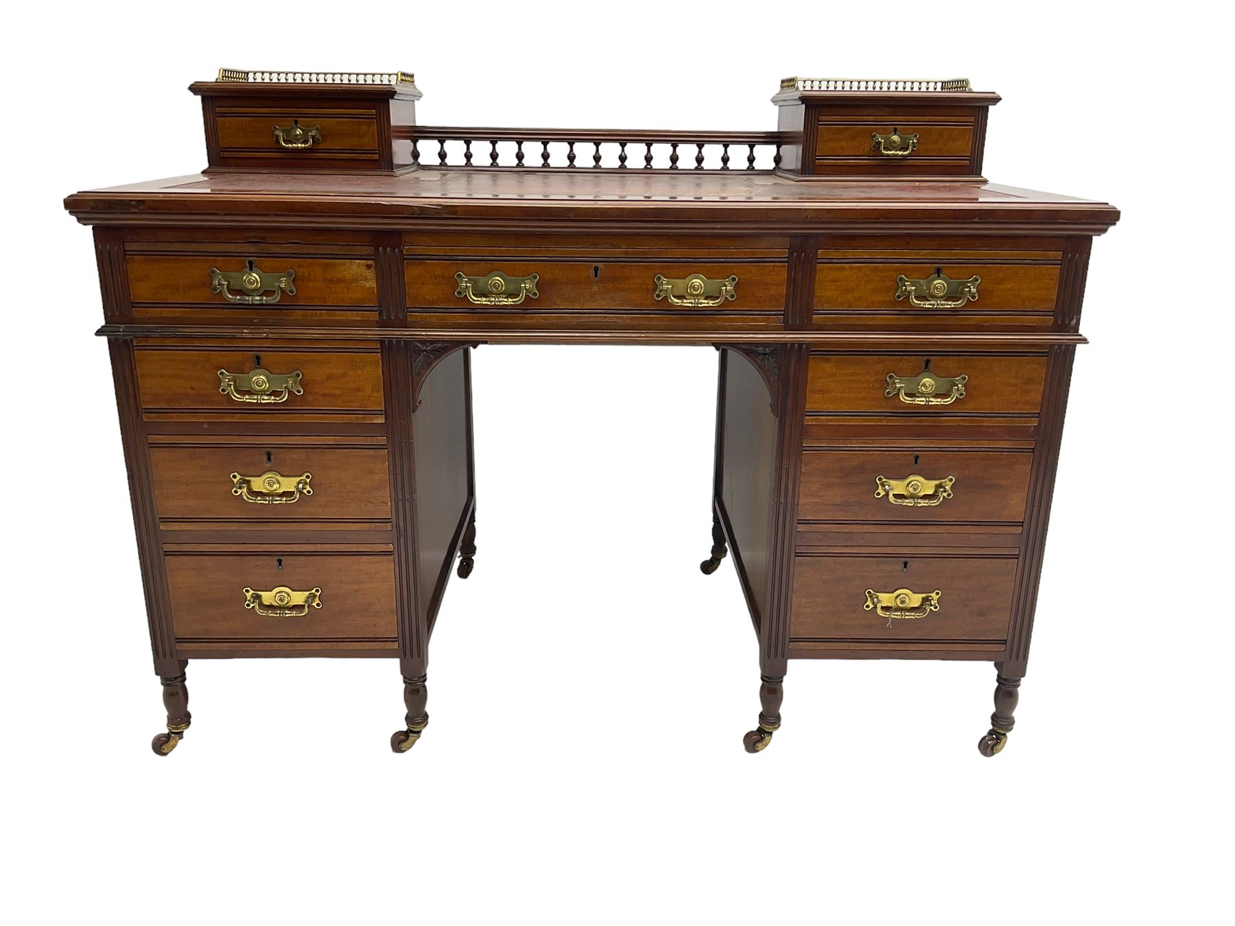Maple & Co - Edwardian mahogany twin pedestal desk, the raised back with spindle gallery and open shelf to centre flanked by two trinket drawers, rectangular top with inset writing surface, fitted with one long and eight short graduating drawers flanked by fluted uprights, raised on brass and ceramic castors, stamped to central drawer