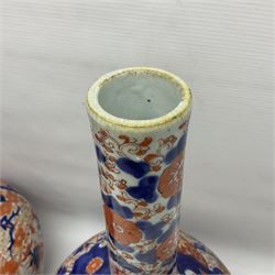 Pair of large 19th century Japanese Imari porcelain bottle vases, painted with shaped reserves of peonies, chrysanthemums and prunus blossom, each H46cm