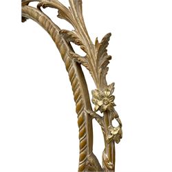 Oval wall mirror in carved and limed beech frame, the pediment carved with ho ho bird encased in interlaced foliate branch, decorated with flower heads and trailing bell flowers