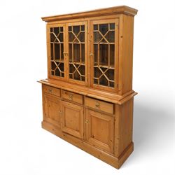 Mid 20th century pine glazed dresser on cupboard base, upper section of rectangular form with three astragal glazed hinged doors enclosing two adjustable wooden shelves and projecting frieze over three short drawers and three hinged panelled cupboard doors with brass handles, the front and sides, raised on a plinth base 