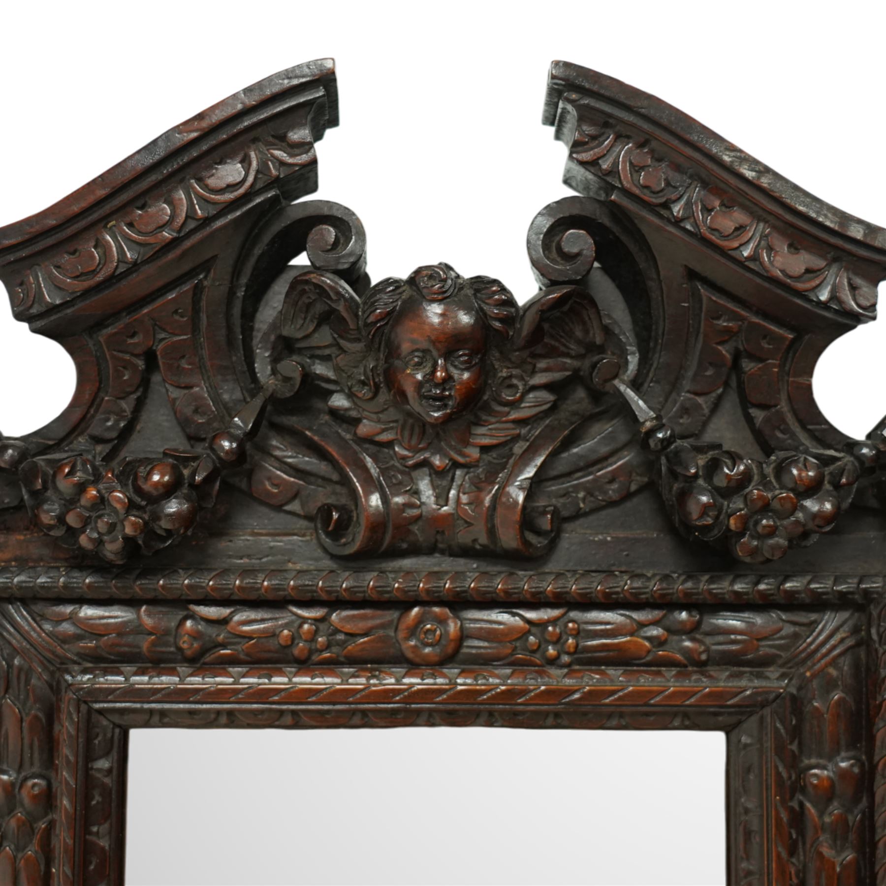 Renaissance-style mid 19th century carved fruitwood wall mirror, carved top surmounted by ‘broken’ arched pediment with central putti figure and grape vine, the sides with two putti figures above C-scroll decorations, and with a similarly carved base