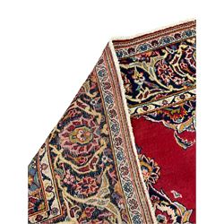 Persian Kashan red ground rug, plain field decorated with floral medallion and spandrels, repeating border with scrolling flower head design 