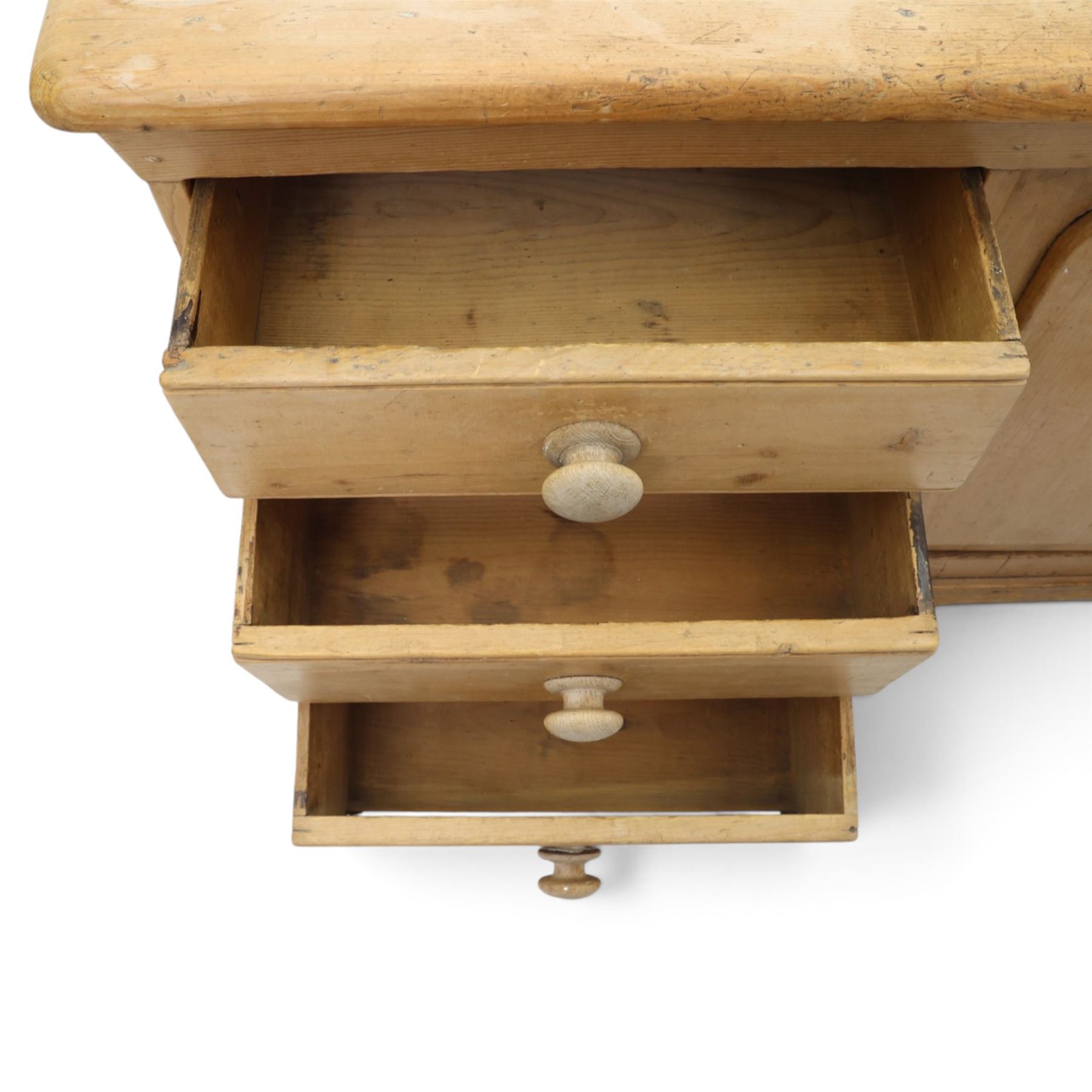 Victorian stripped pine sideboard, rectangular plank top rounded edges, with central cupboard door with shaped panel, flanked by two banks of three graduating drawers with turned knobs, raised on a plinth base 