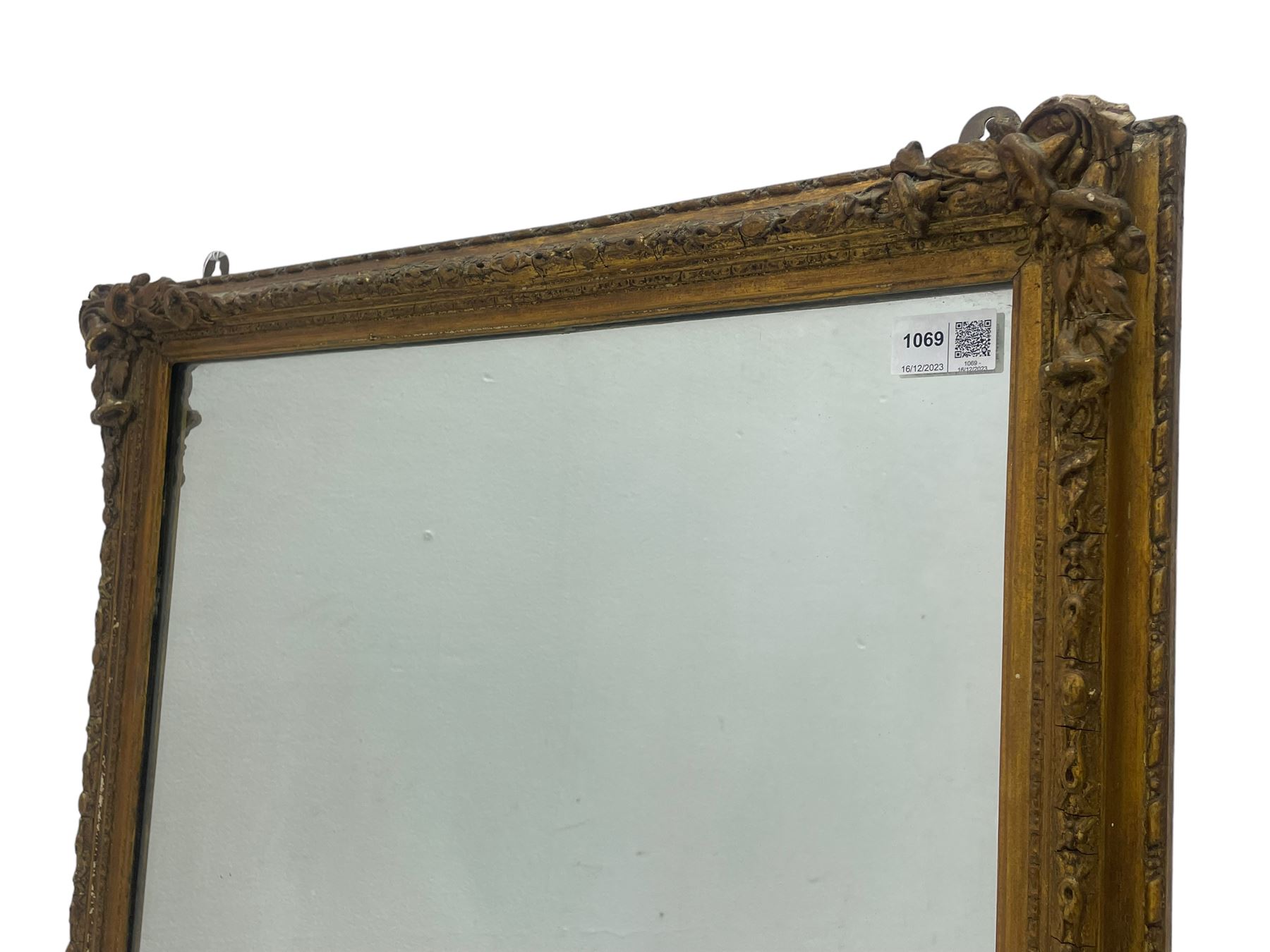 19th century gilt framed wall mirror, the corners decorated with flower heads with extending foliage, plain mirror plate