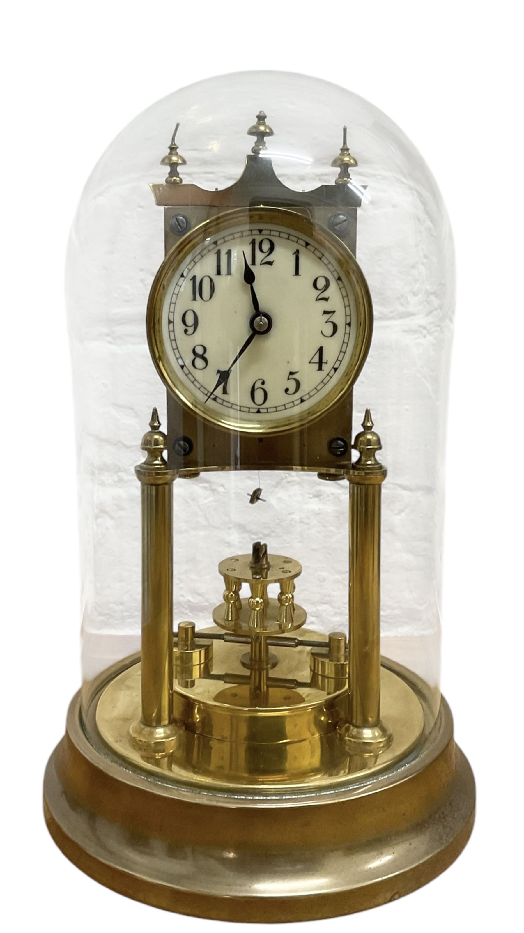 Gustav Becker - German early 20th century torsion clock, with a skeleton movement and rotary oscillating pendulum, enamel dial with Arabic numerals , minute markers and steel spade hands, on a circular brass base with a glass dome, serial No 2173866, with torsion spring complete and in place. With key.