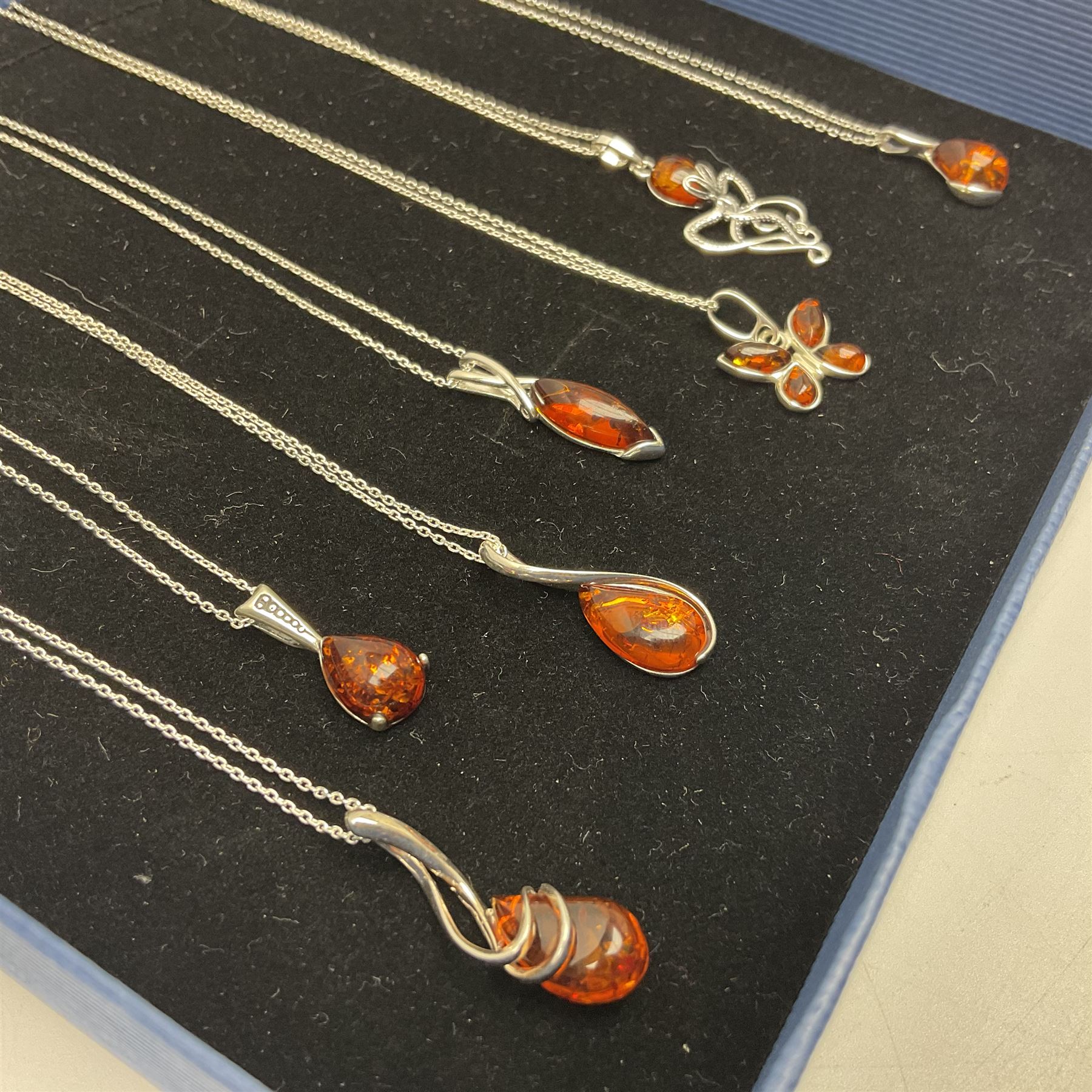 Seven silver Baltic amber pendant necklaces, including octopus and butterfly designs, all stamped 925 