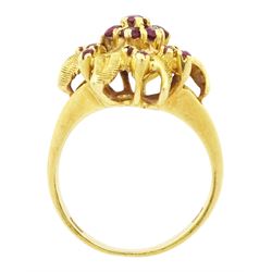 18ct gold ruby flower head cluster ring, seven round cut rubies surrounded by textured leaves, each spaced by two rubies, stamped 750