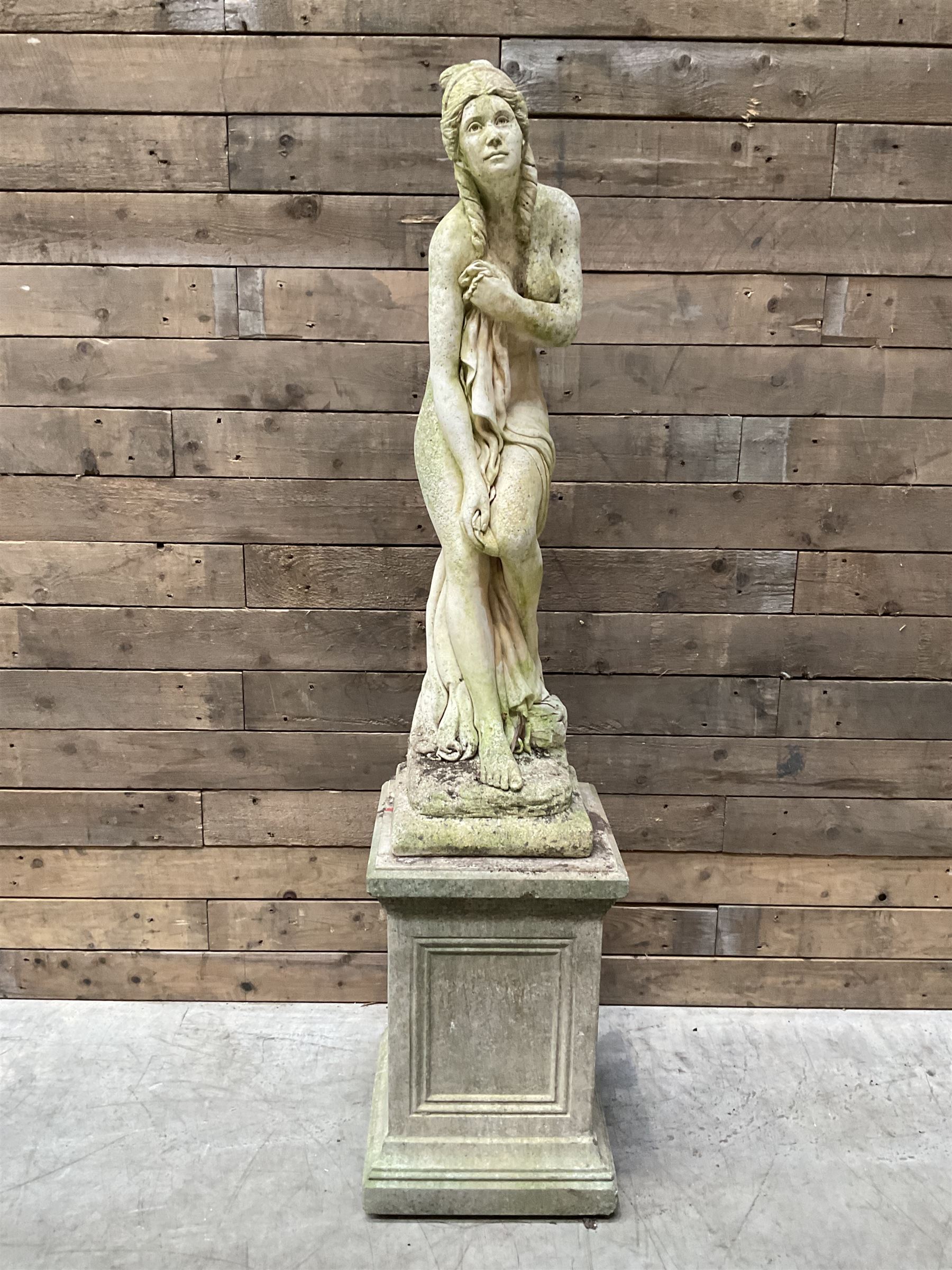 Cast stone garden figure of a bathing lady, raised on square plinth