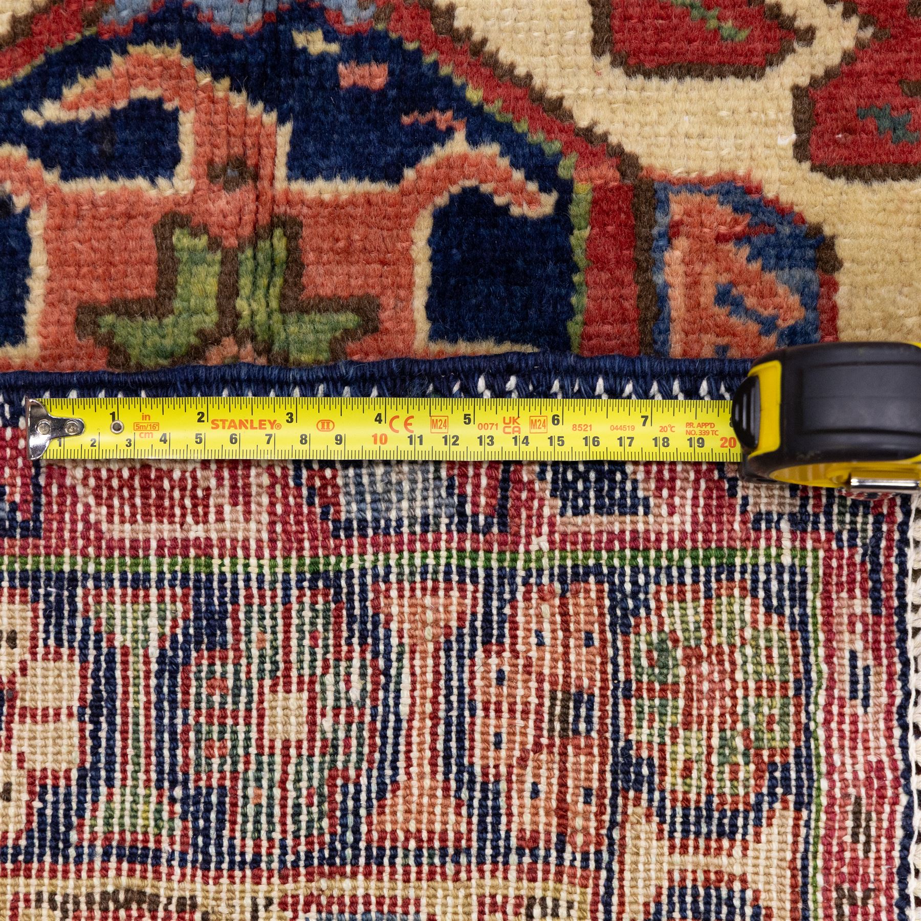 North West Persian Karajeh hand-knotted runner, madder red field, decorated with a vertical sequence of bold geometric medallions, interspersed with stylized floral and tribal motifs, framed by a dark ground border of angular palmettes and rosettes with multiple guard stripes, with cotton fringe ends 