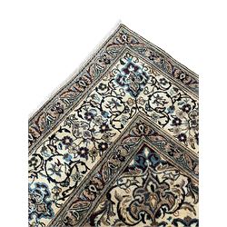 Persian Kashan ivory ground carpet, central rosette medallion surrounded by swirling leafy branches and floral sprays, the main border with scrolling pattern interspersed with floral motifs, within guard stripes 