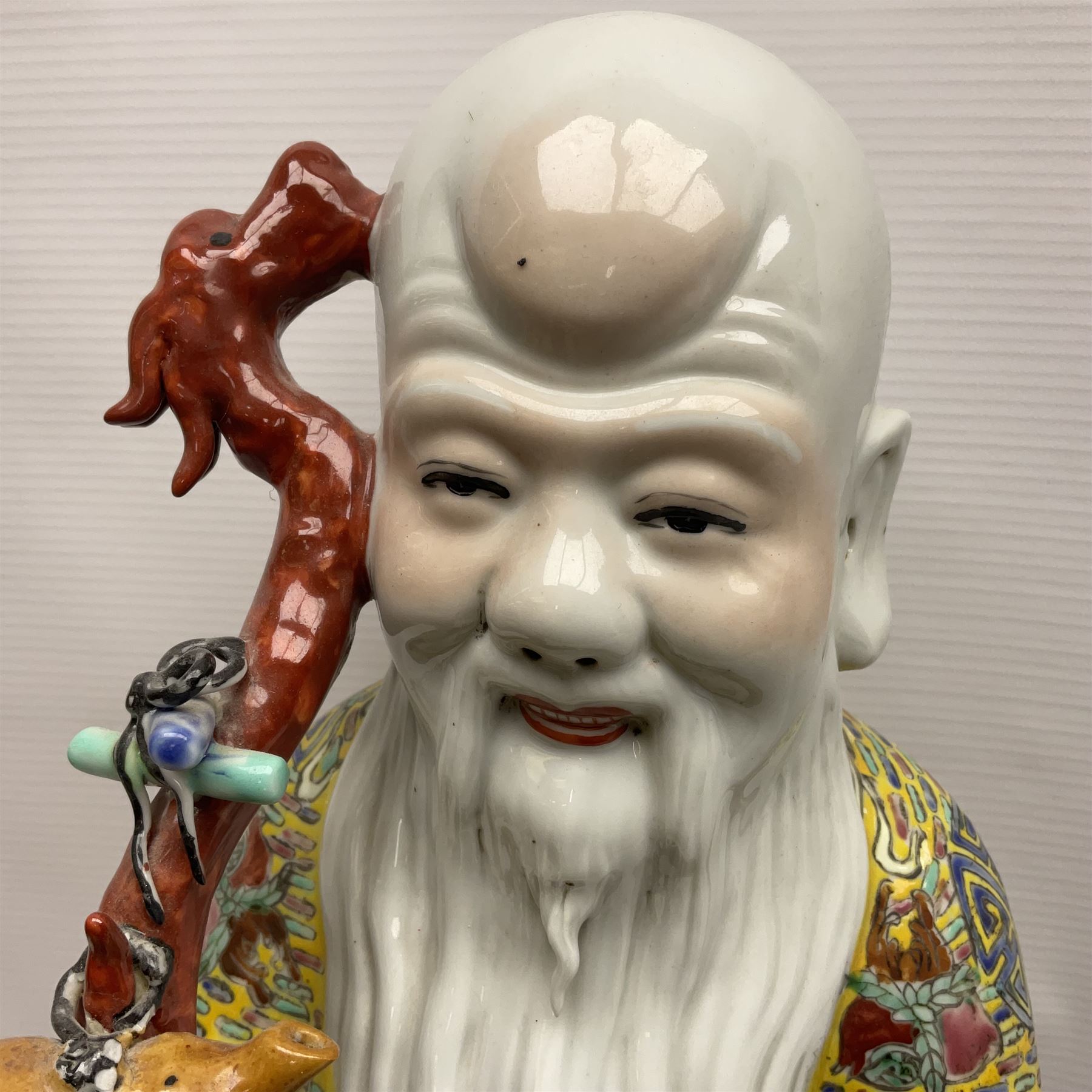 Chinese Republic Period porcelain figure, modelled as Shoulao, wearing elaborately enamelled robes decorated with peaches and flower heads, with impressed mark beneath, H55cm