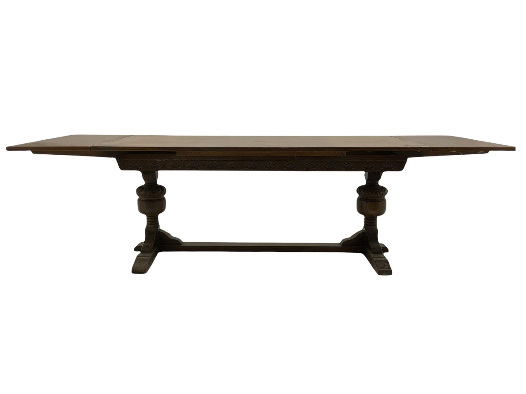 20th century oak drawer leaf extending dining table, two foliage carved baluster supports on sledge feet joined by floor stretcher 