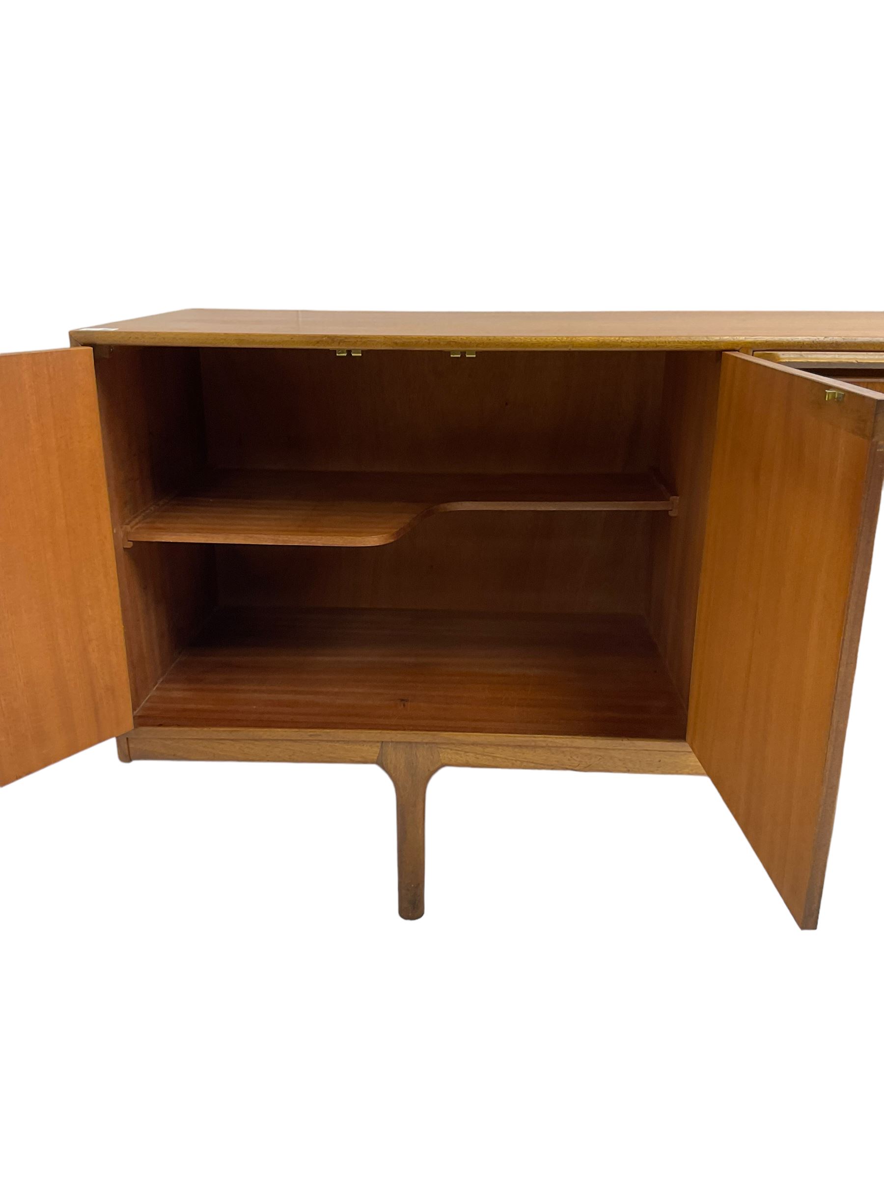 Tom Robertson for AH McIntosh & Co of Kirkaldy - mid-20th century teak sideboard, fitted with four central drawers, flanked by cupboard enclosing shelves and sliding tray, raised on cylindrical supports