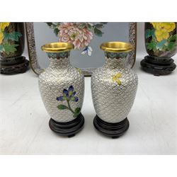 Six cloisonné vases, to include two pairs decorated with peonies and foliage on patterned gilt ground, all with carved hardwood stands, another of slender ovoid form decorated with birds upon blossoming branches on vibrant blue ground, etc, together with a square cloisonné tray, L17.5cm