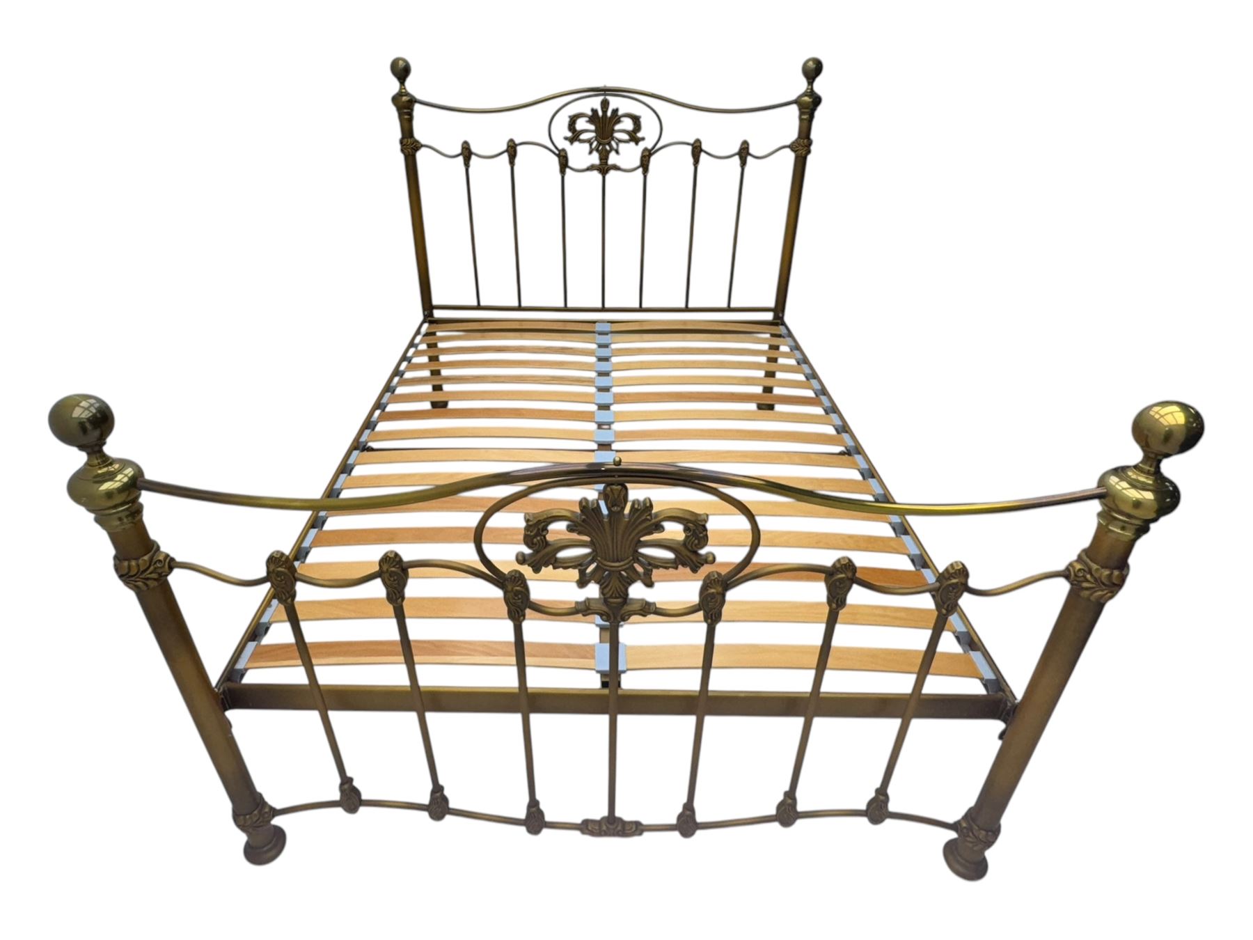 Victorian design king size brass bed frame, featuring an arched headboard and footboard with intricate cast floral and scrollwork centre motifs, flanked by cylindrical supports with ball finials and decorative collars, raised on rounded feet, with a slatted wooden base