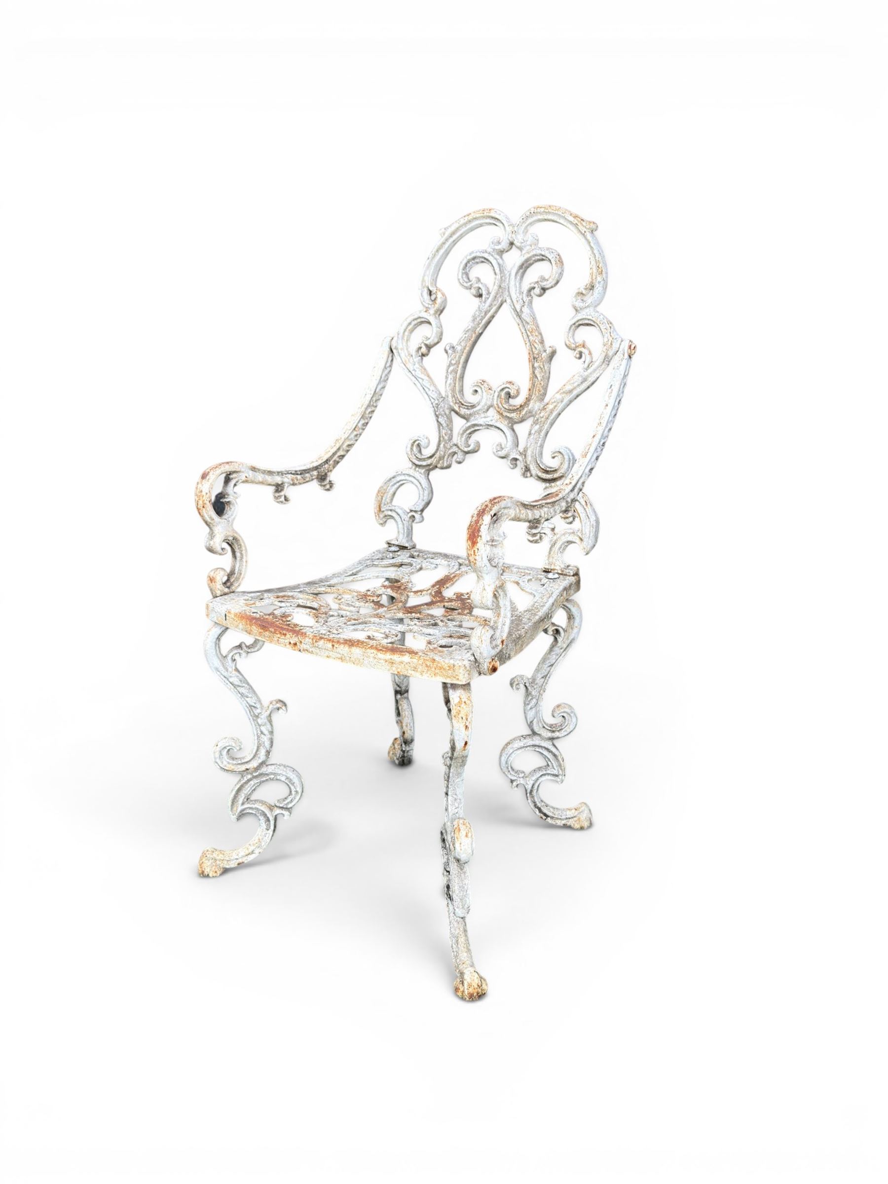 Pair of Victorian cast iron garden chairs, the ornate pierced back of scrolling foliate design, scrolling arm terminals over splayed supports formed of C and S-scrolls, in distressed white painted finish