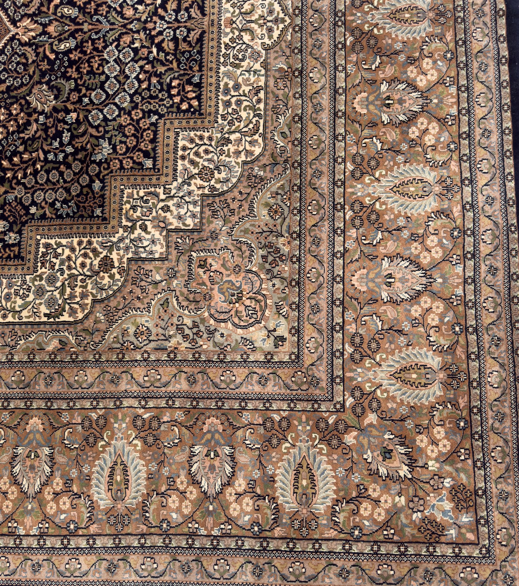 Large Persian indigo ground rug, the busy field decorated with trailing branches and flower heads, peach border decorated with palmettes -