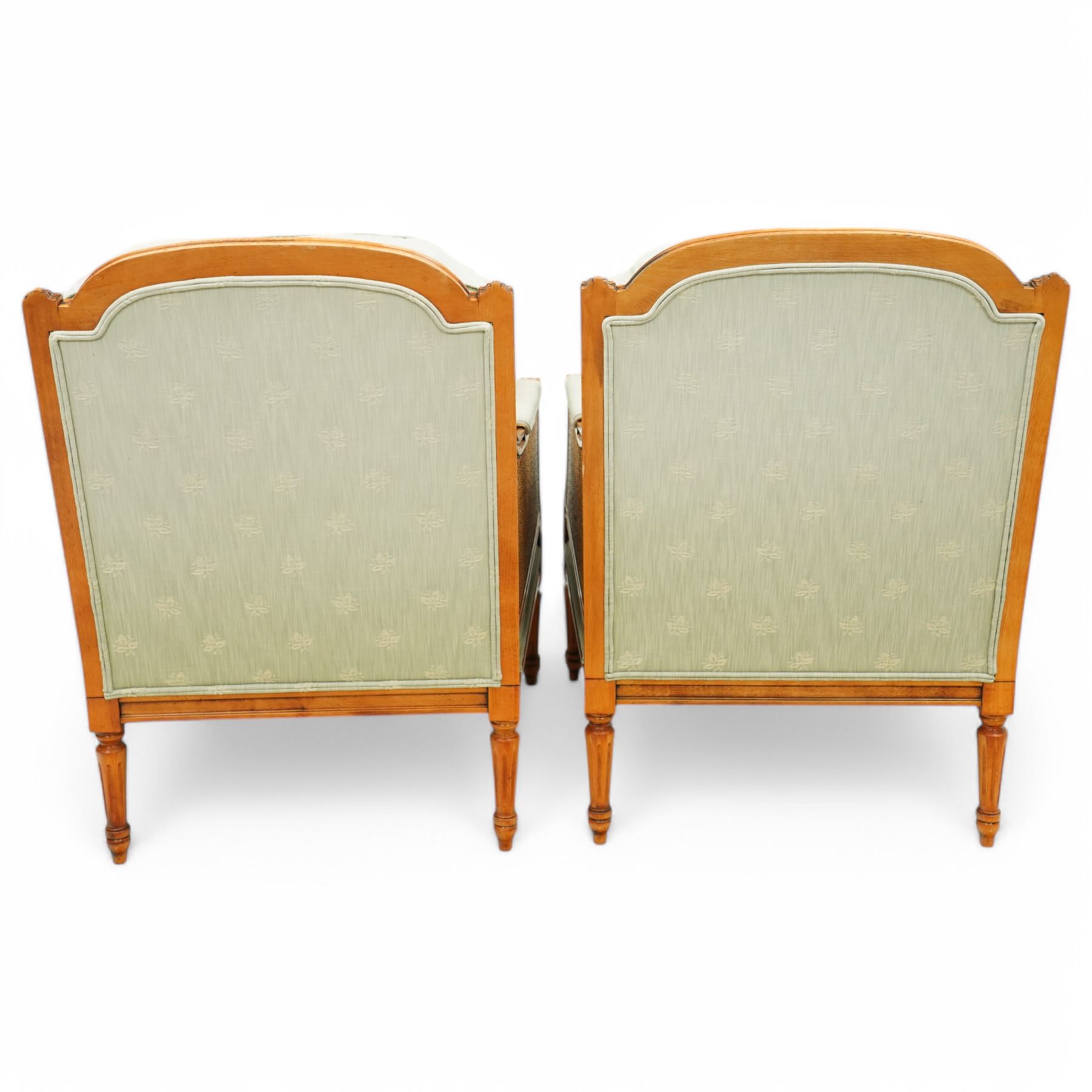 French Empire design varnished wood three piece lounge suite comprising of two cane armchairs and matching sofa, carved top rails with foliate terminals, cane side panels and padded scroll arms, upholstered in a green brocade with matching piping, on fluted legs