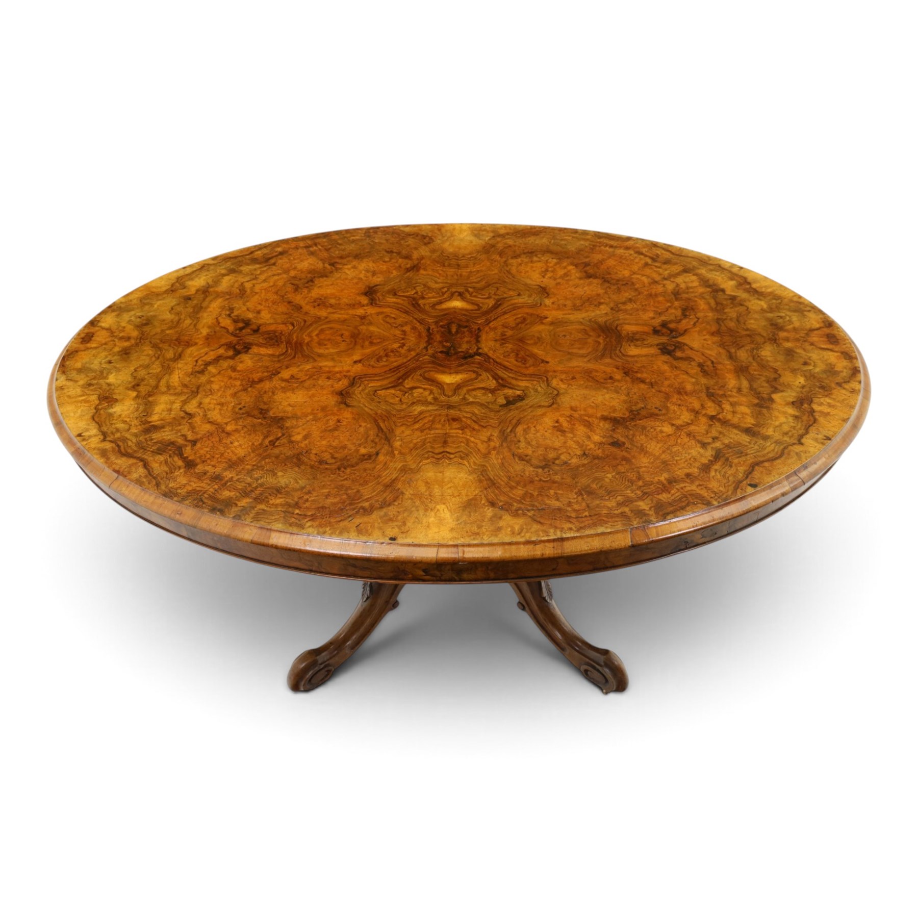 Victorian figured and burr walnut loo table, oval book-matched veneer top with moulded edge, over a turned octagonal pedestal terminating to four splayed supports with flowerhead carved knees and scroll feet with castors