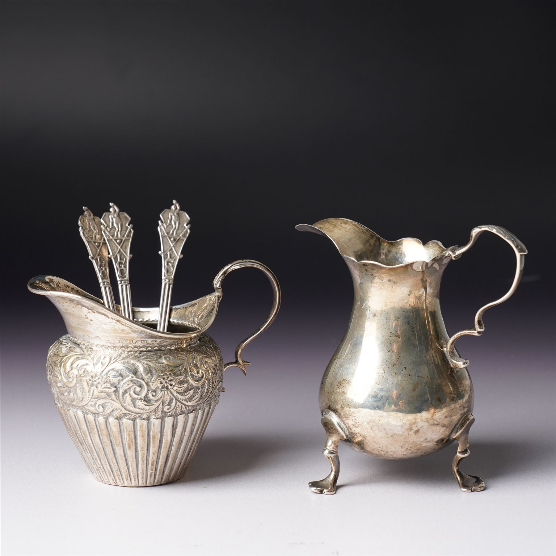 George III silver cream jug with crimped rim and scroll handle, Victorian silver cream jug with embossed decoration Birmingham 1888 and three silver golf spoons Birmingham 1961