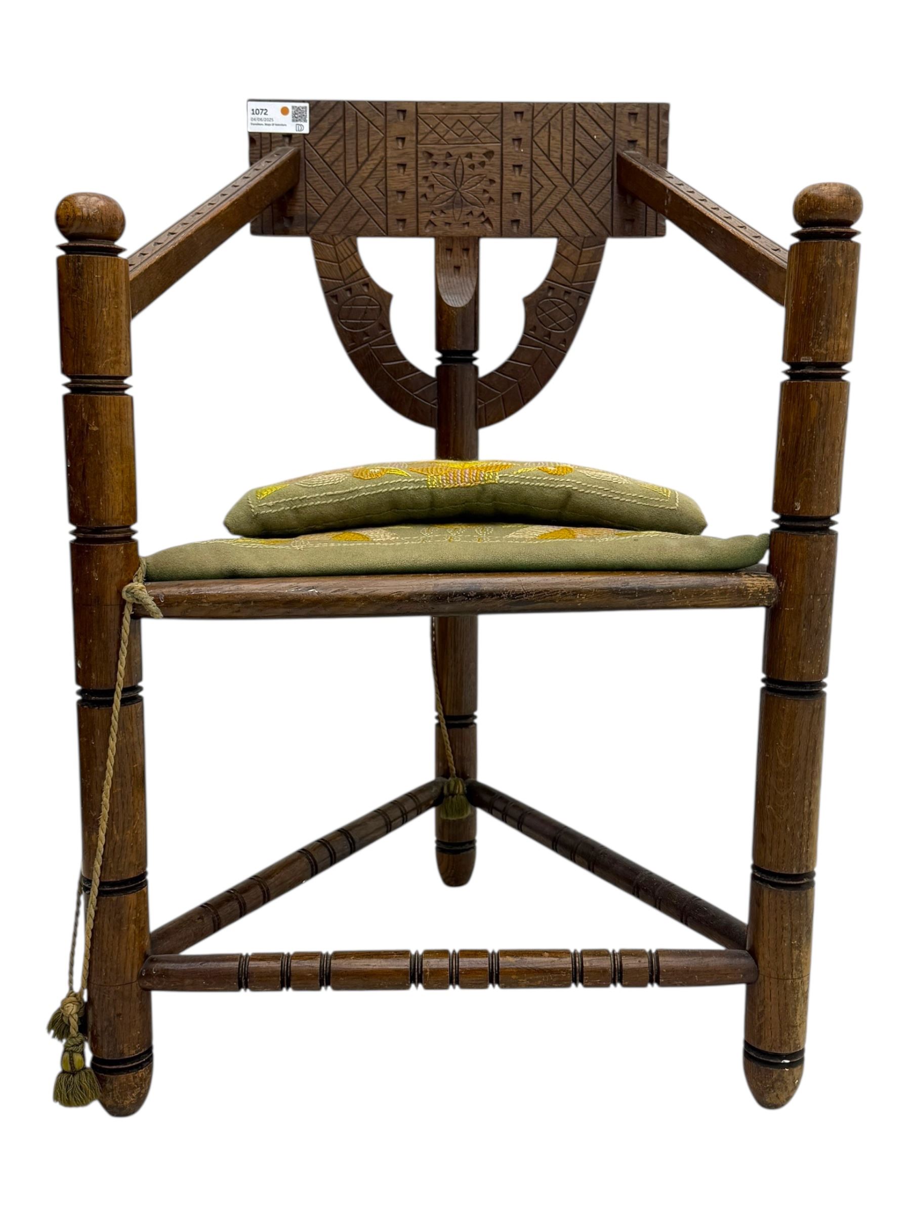19th century swedish monk's chair, the oak frame with triangular seat and sloped arms, the backrest carved with geometric chipwork and a central pierced medallion 