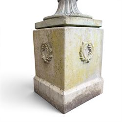 Cast stone classic garden urn, the rim decorated with leaves and berries, twin handles with face masks, raised on square base, stamped HGC