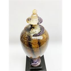 Early 19th century and later Blue John urn, Winnats one vein, of ovoid form with integrated cover and ball finial, upon a spreading circular base, and square stepped black lacquered base, H34.5cm