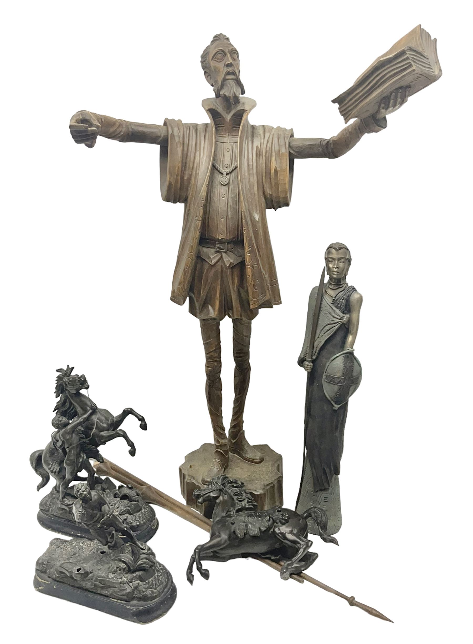 Spanish carved figure of Don Quixote, holding a book, base stamped 'Ouro, together with two spelter figures and one other