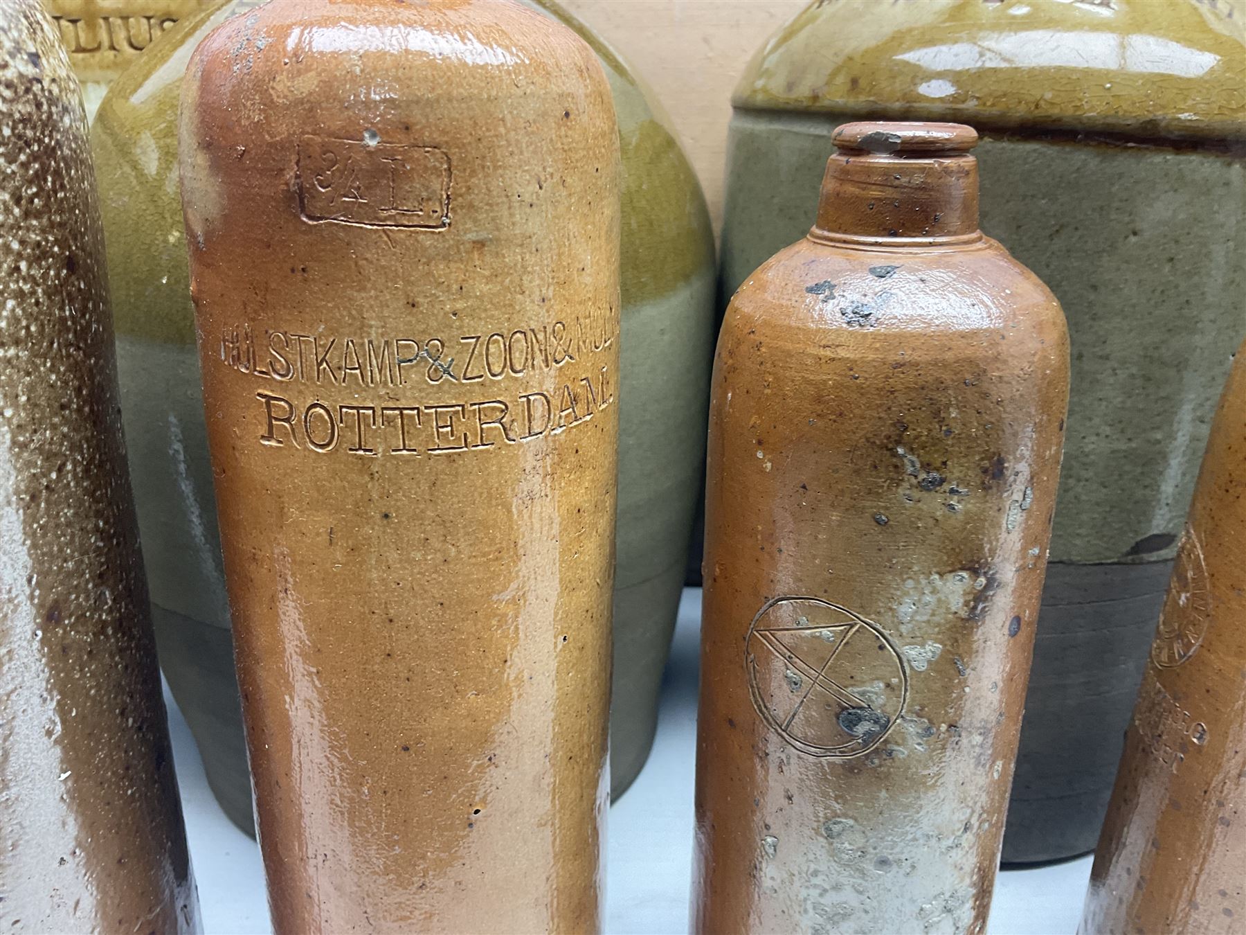 Quantity of stoneware flagons, to include Skipton, Clitheroe and Hellifield related examples, four salt glazed bottles, large cylindrical stoneware jar, large twin handled jar and vase, together with two brass jam pans, tallest H35cm