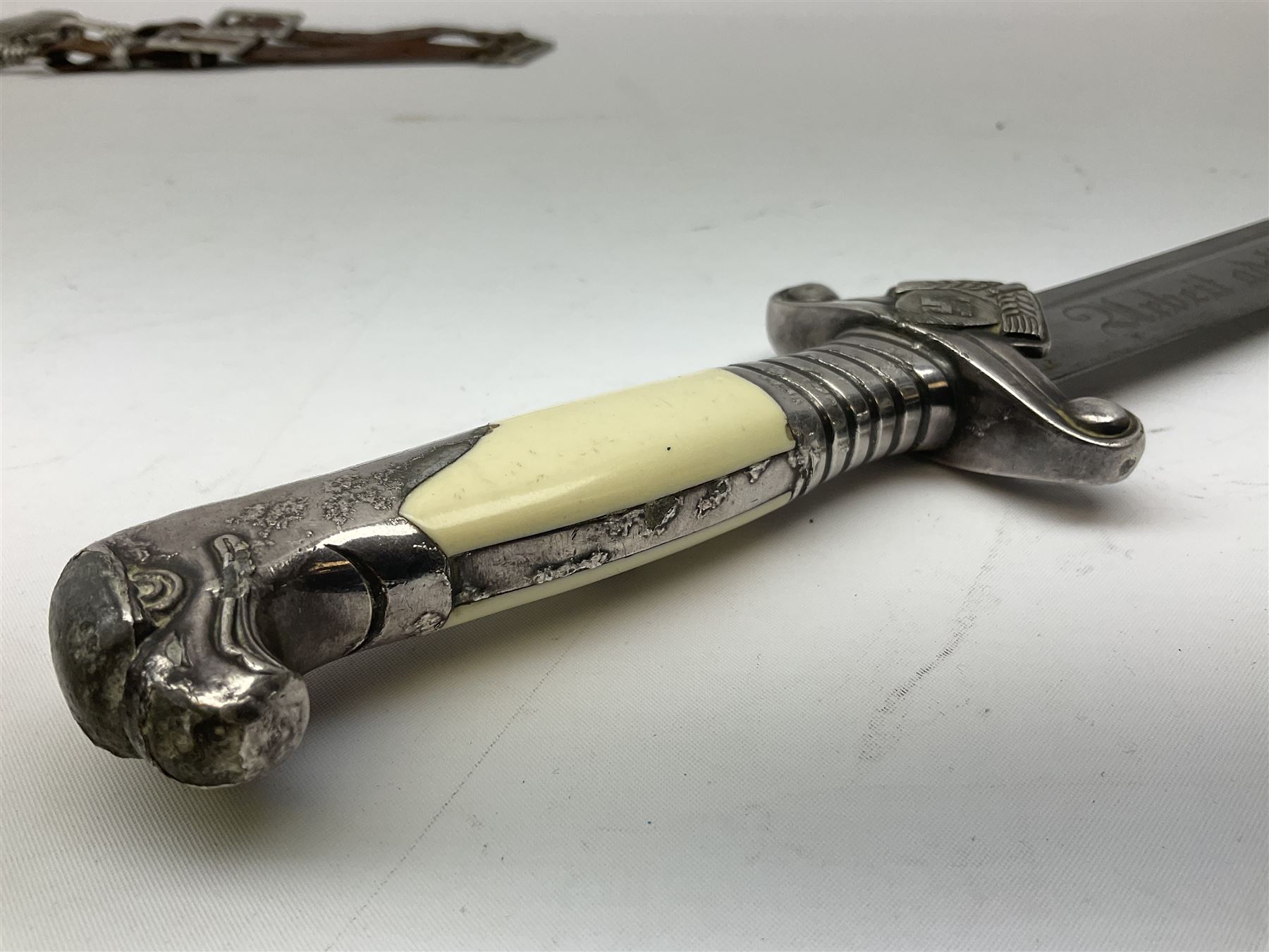 German Reichsarbeitdienst RAD Leader's Hewer dagger, the 26cm single edged scimitar shaped blade with narrow fuller, etched Arbeit adelt; by E.D. Wusthof, Solingen; the aluminium hilt with spade and wheat ear langet; two piece white plastic grip and eagle head pommel; pebbled steel scabbard engraved with ears of wheat and strapwork with double leather hangers L40cm overall