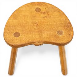 Mouseman - oak three-legged stool, dished kidney-shaped seat with burr inclusions, raised on three octagonal splayed supports, with carved mouse signature, by the workshop of Robert Thompson of Kilburn