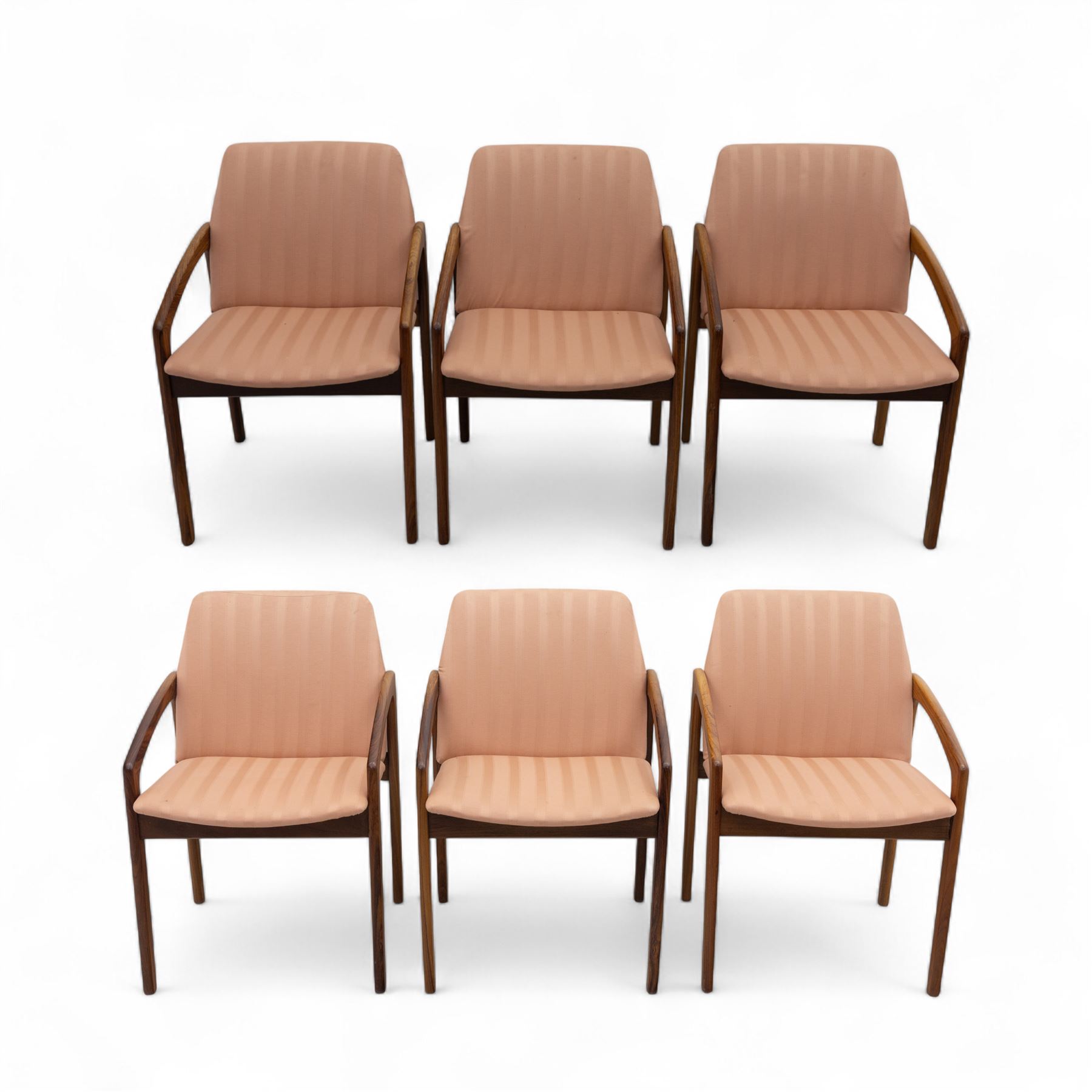 Mid-20th century Danish teak armchairs, each with curved open arms and upholstered seat and backrest in salmon pink striped fabric, raised on tapering legs