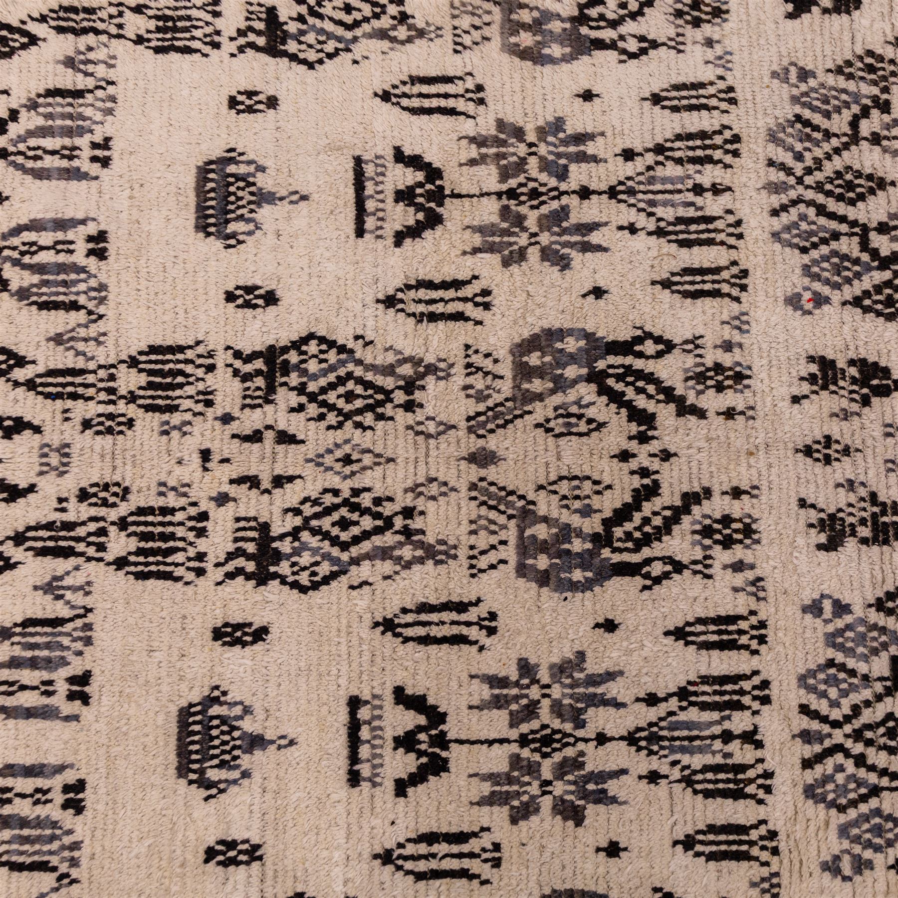 Moroccan hand-knotted Berber rug, of rectangular form, ivory ground woven with horizontal bands of stylized tribal motifs, including abstract animals and anthropomorphic figures, interspersed with geometric devices, with fringe ends 