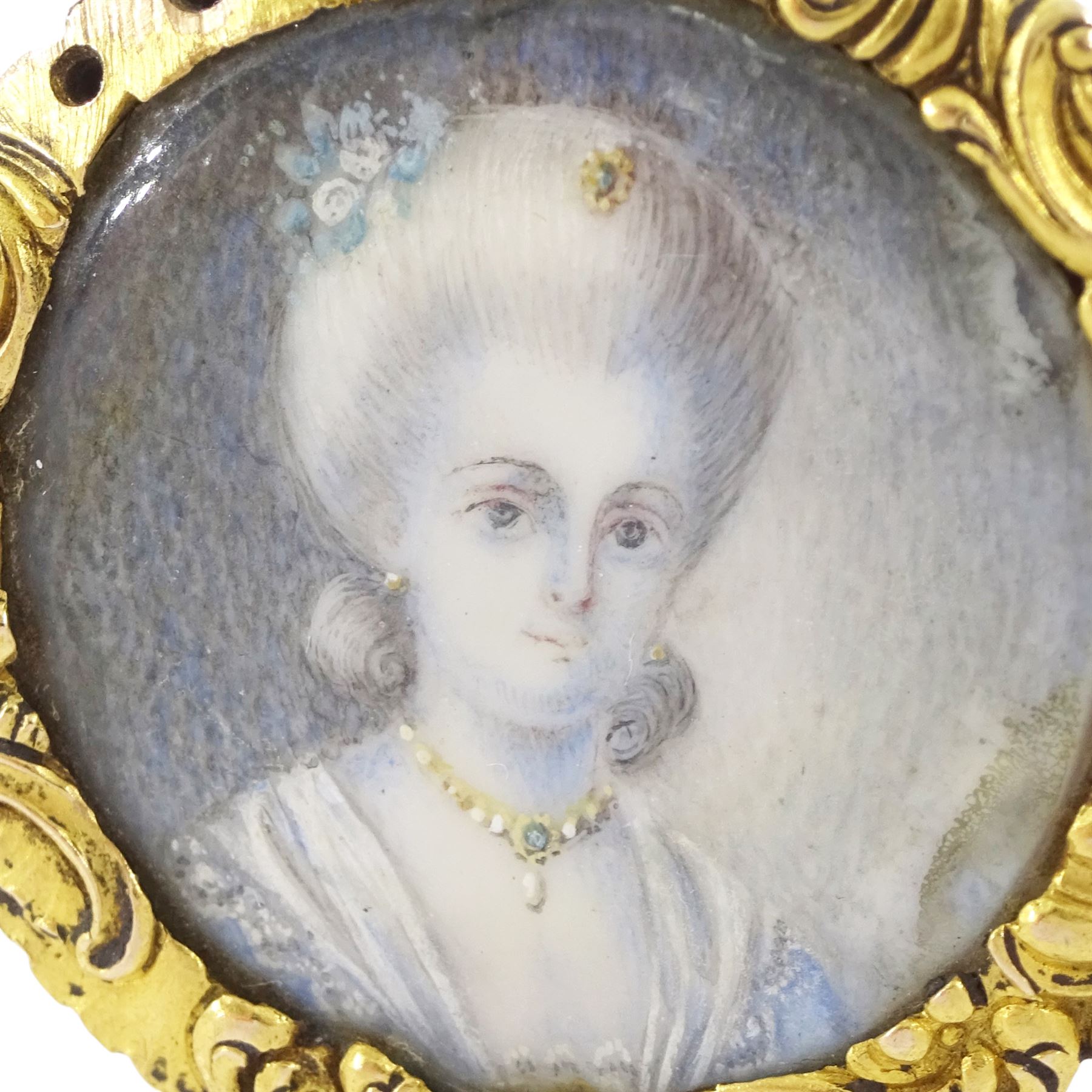 19th century gold portrait ring, set with a circular miniature of a young woman in 18th century dress on ivory, under a glazed panel, within a gold scroll frame and pierced gallery. This lot has been registered for sale under Section 10 of the APHA Ivory Act