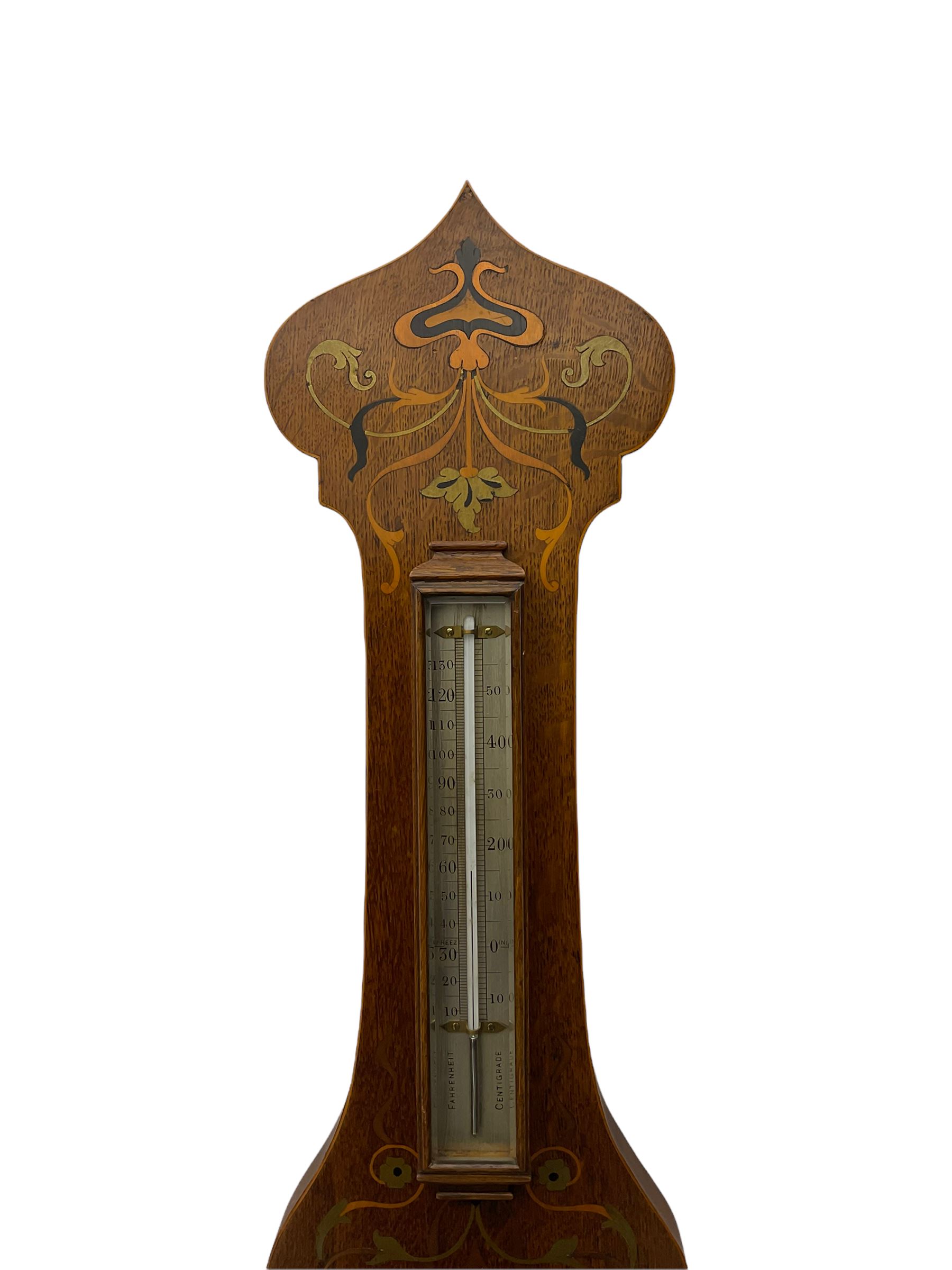 An early 20th century oak cased aneroid barometer in a decorative form