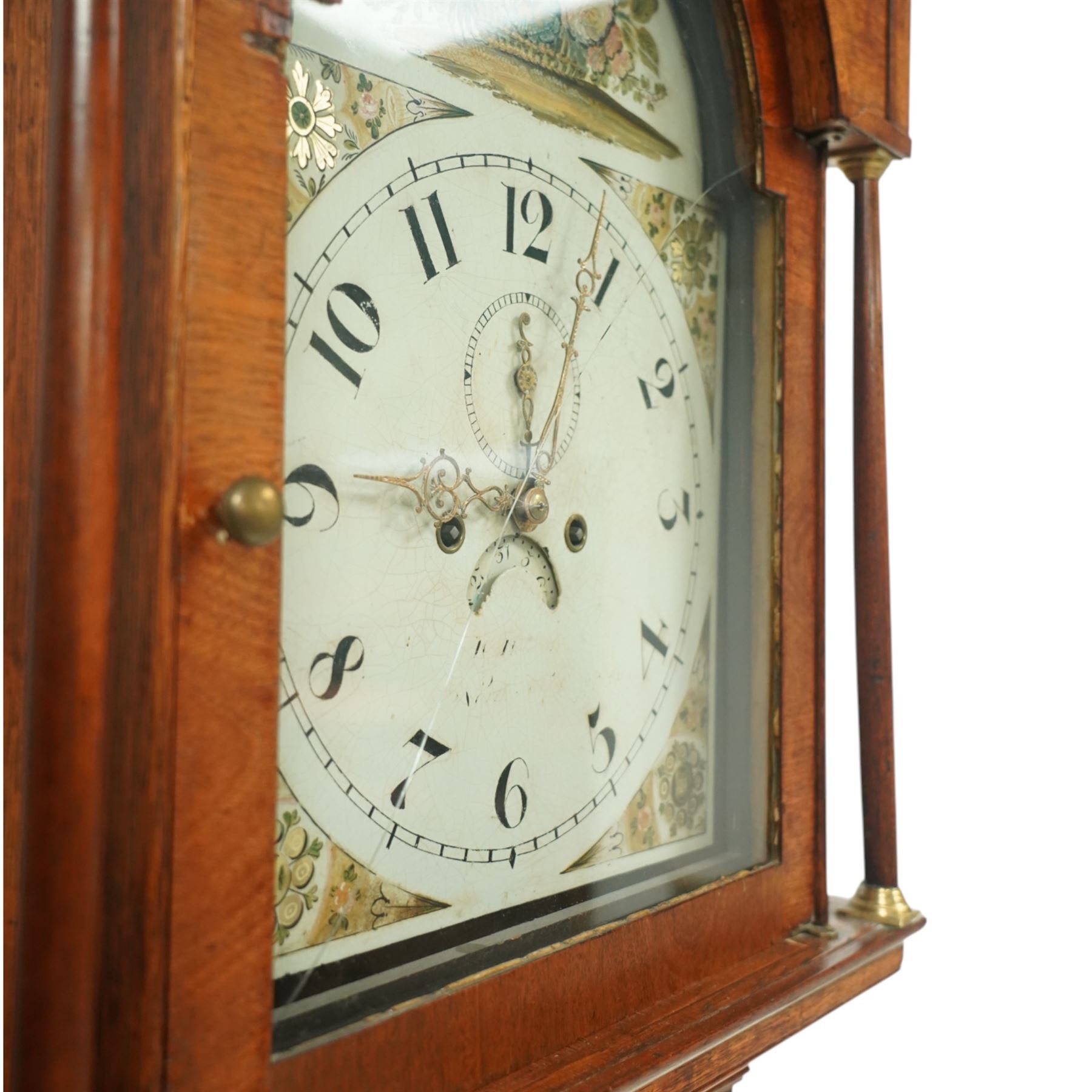 19th century-Oak and Mahogany 8-day longcase clock c 1820 (maker indistinct) with an open carved swan necked pediment and central finial, hood door flanked by turned pilasters, trunk with canted corners and a plain rectangular door, plinth with crossbanding and raised on bracket feet, painted dial with tumbling Arabic's, floral spandrels and conforming decoration to the arch, with a seconds hand, date aperture and brass stamped hands, dial pinned to a rack striking movement striking the hours on a bell. With weights & pendulum.