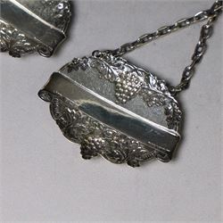 Silver bottle coaster, of circular form with turned wooden centre and pierced sides, hallmarked LGS, London 1977, together with two decanter labels, each with embossed grape vine decoration engraved Scotch and Sherry, hallmarked 
