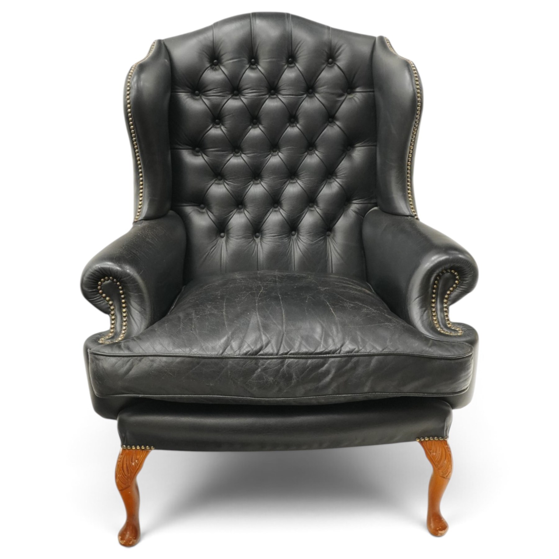 Pair of quality Georgian design wingback club armchairs, the high arched back with wings over rolled arms, upholstered in back-buttoned black leather with loose seat cushion, raised on foliate carved cabriole supports