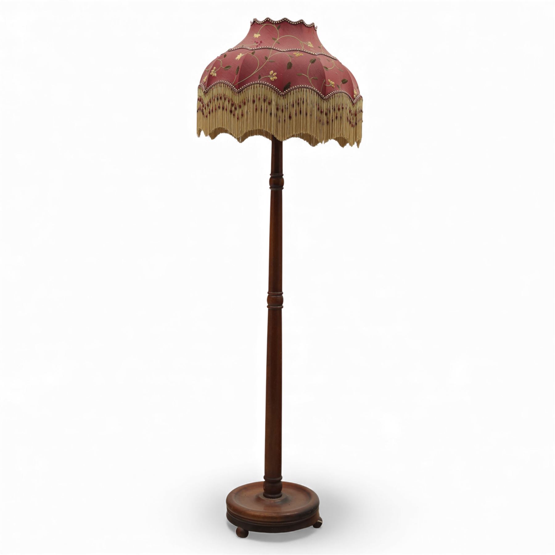 Early 20th century mahogany standard lamp, the turned column raised on a circular stepped base with compressed bun feet, fitted with a shaped Downton Abbey silk shade decorated with foliate trail motifs, beaded edging and fringe trim